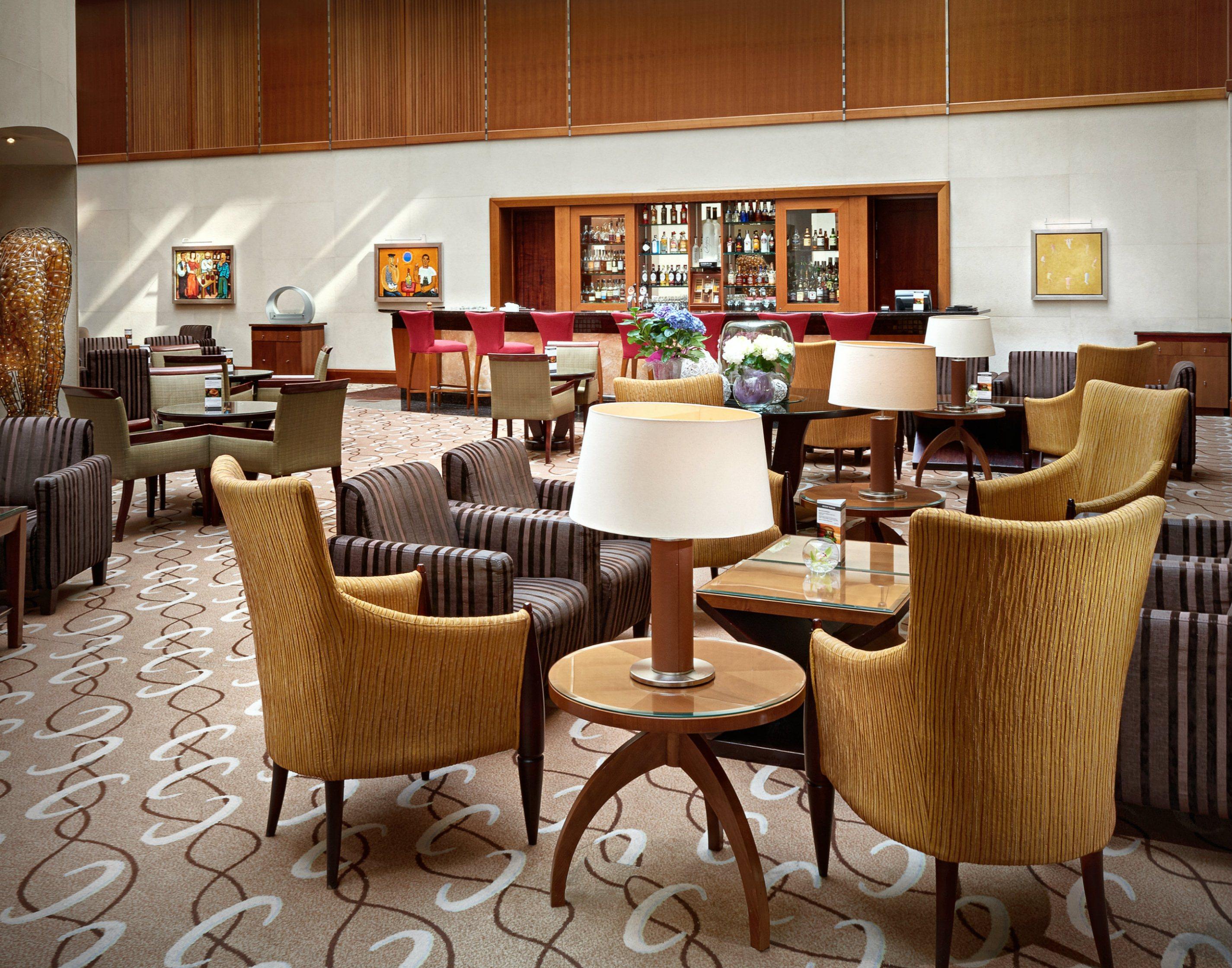 Regent Warsaw Hotel Exterior photo The photo shows a stylish and modern lounge area, likely within a hotel or upscale establishment. The seating consists of several chairs, predominantly in shades of brown and gold, arranged around small tables. A few lamps are placed on the tables, p