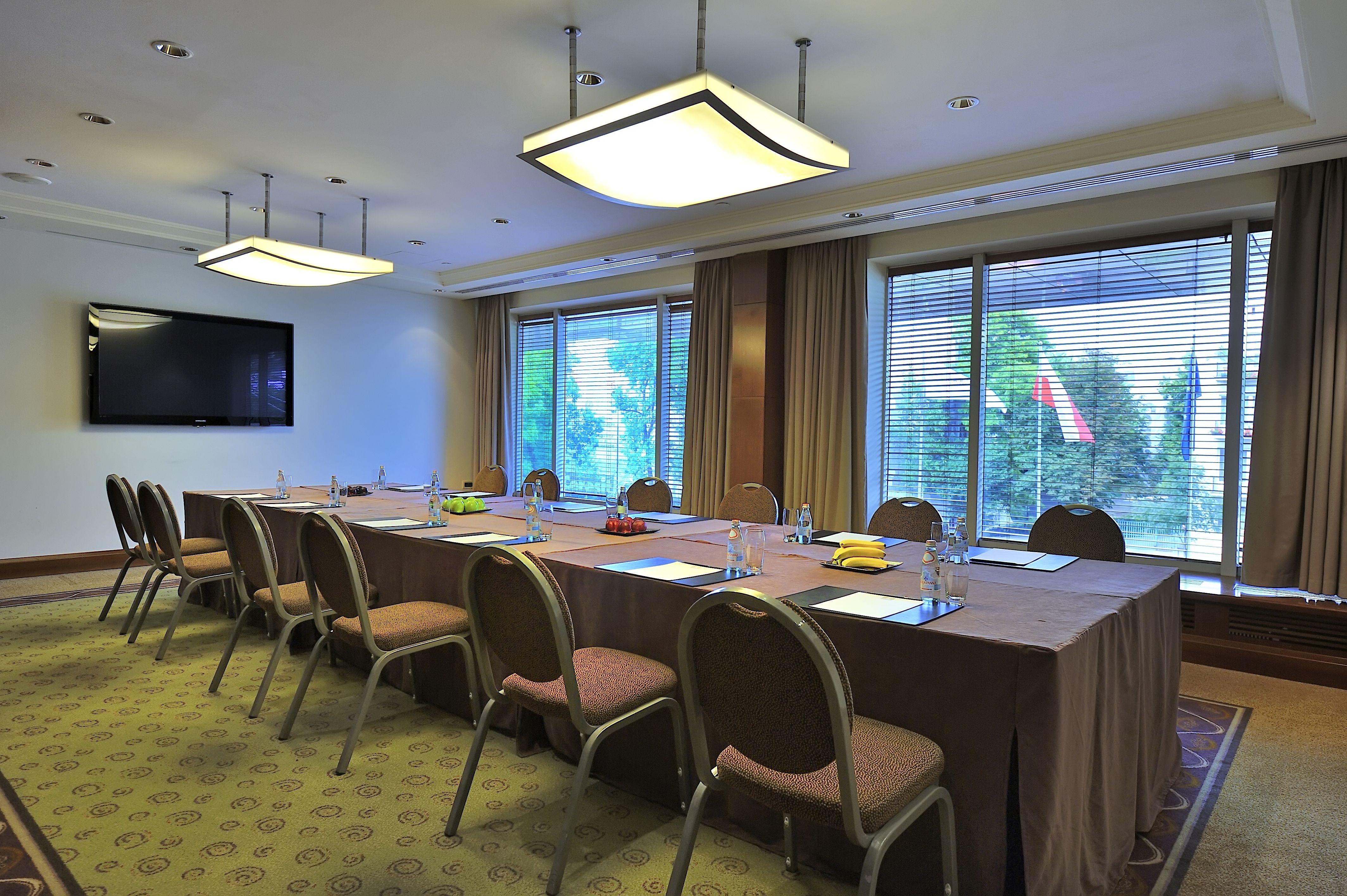 Regent Warsaw Hotel Exterior photo The photo shows a conference room set up for a meeting. There is a long table covered with a brown tablecloth, surrounded by several chairs. On the table, there are items likely for the meeting, such as notepads, pens, and some fruit or snacks. The r