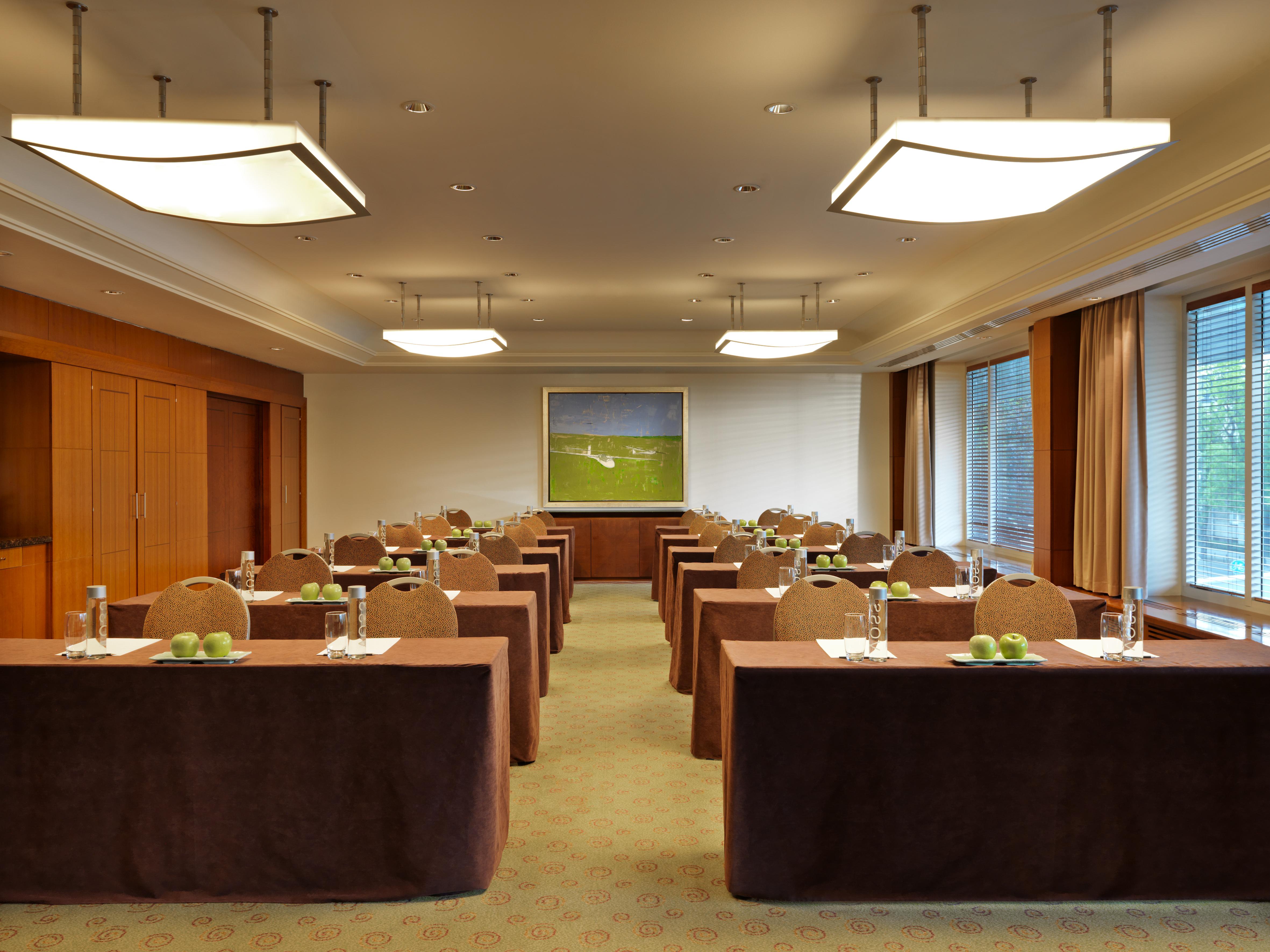 Regent Warsaw Hotel Exterior photo The photo depicts a conference or meeting room. The room is arranged with several rectangular tables set up in rows, each covered with brown tablecloths. On each table, there are glass water bottles and small green apples, suggesting preparation for 