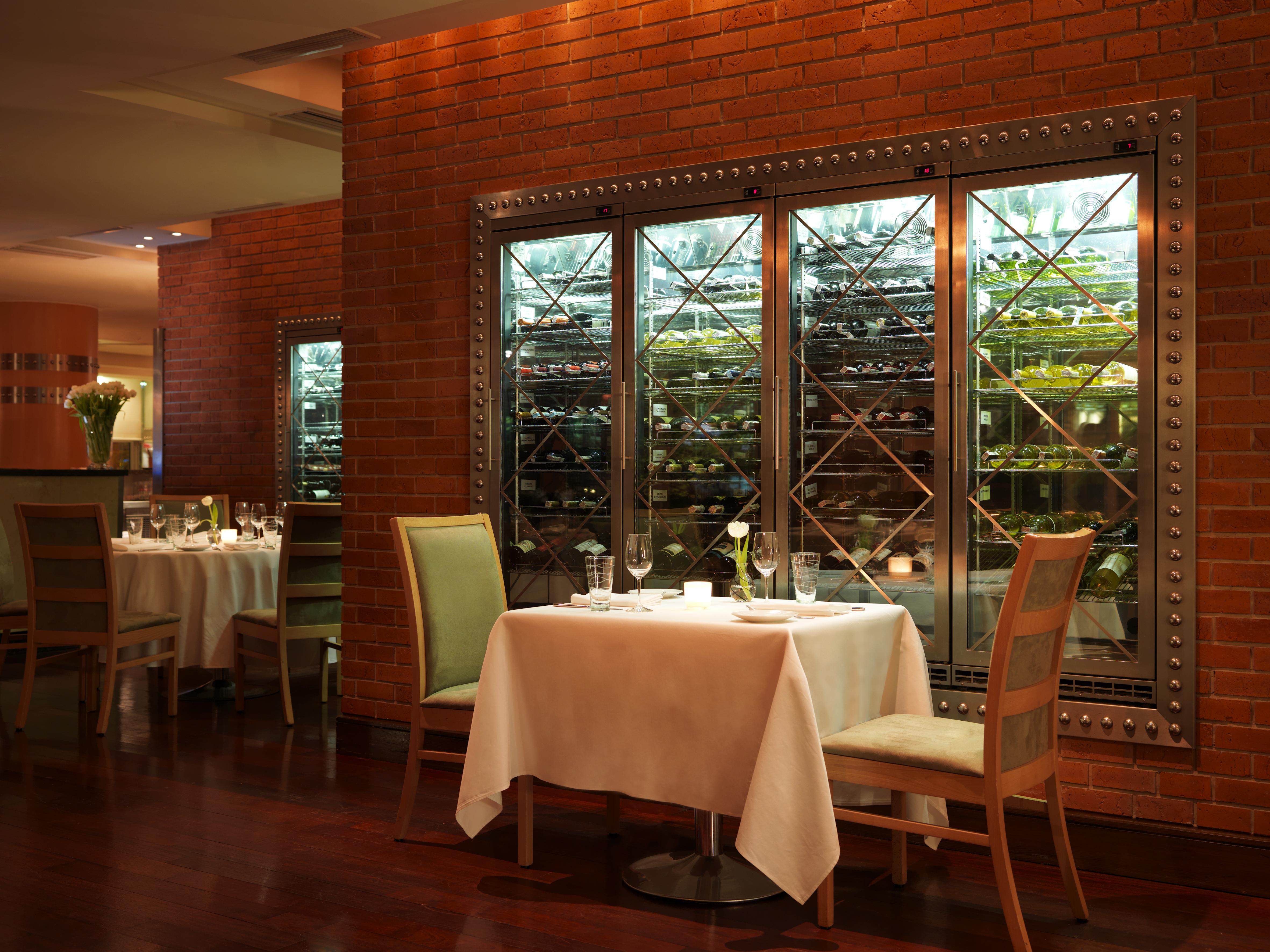 Regent Warsaw Hotel Exterior photo The photo shows an elegant dining setting in a restaurant. There are two tables, each elegantly set with white tablecloths and fine dining utensils, including glasses and plates. The ambiance is warm, with wooden flooring and a backdrop of exposed br