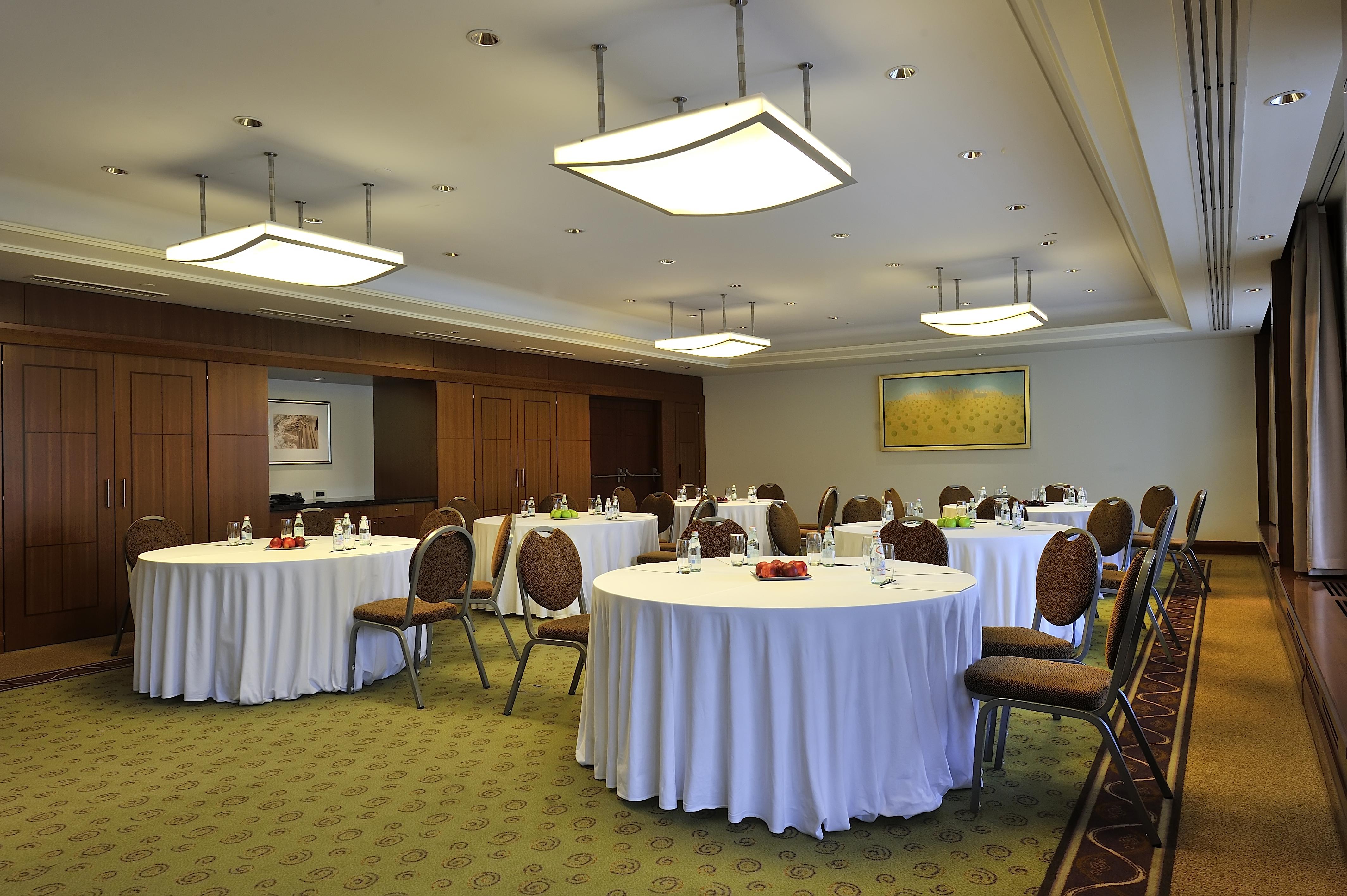 Regent Warsaw Hotel Exterior photo The photo depicts a conference or meeting room. It features several round tables covered with white tablecloths. Each table has chairs around it, and there are items such as water bottles and possibly snacks on the tables. The room has modern lightin