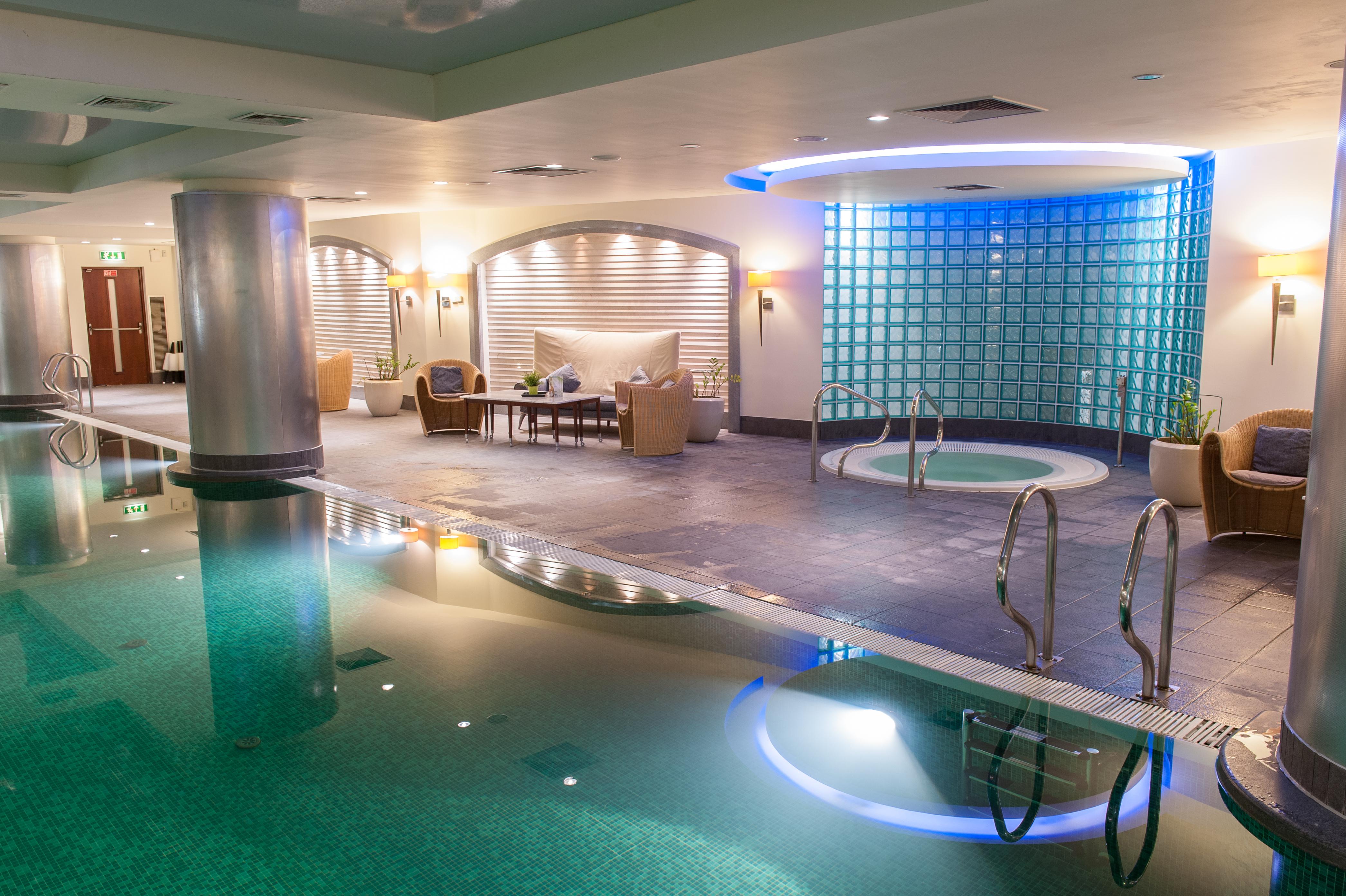 Regent Warsaw Hotel Exterior photo The photo shows a spa area featuring a calm and relaxing atmosphere. There is a swimming pool with clear water reflecting the soft lighting. To one side, there is a hot tub with steps leading into it. The walls are adorned with light-colored material