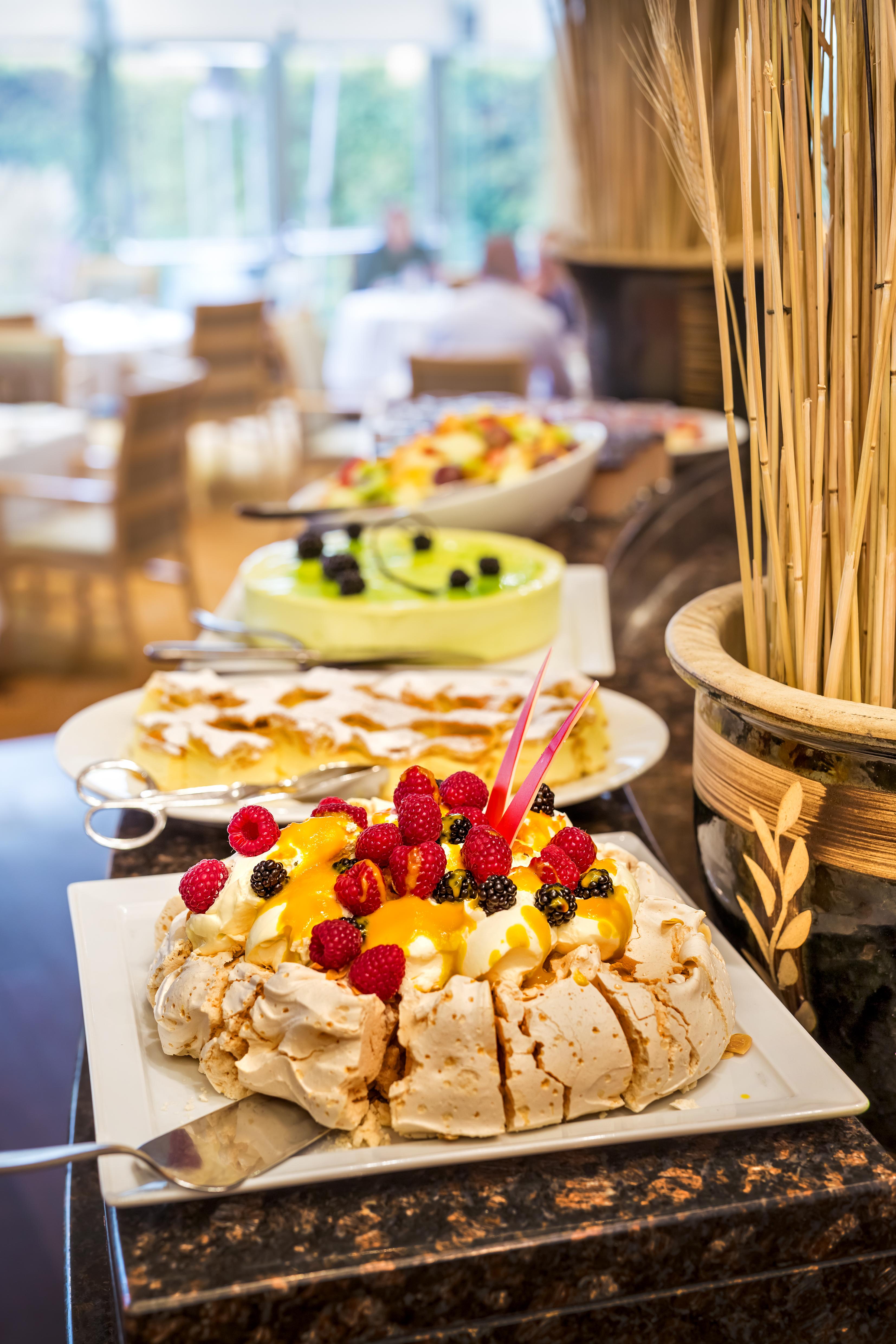 Regent Warsaw Hotel Exterior photo The photo shows a buffet display of various desserts. In the foreground, there is a large dessert topped with an assortment of colorful fruits, including raspberries, blackberries, and orange slices. This dessert is likely a type of meringue or pavlo