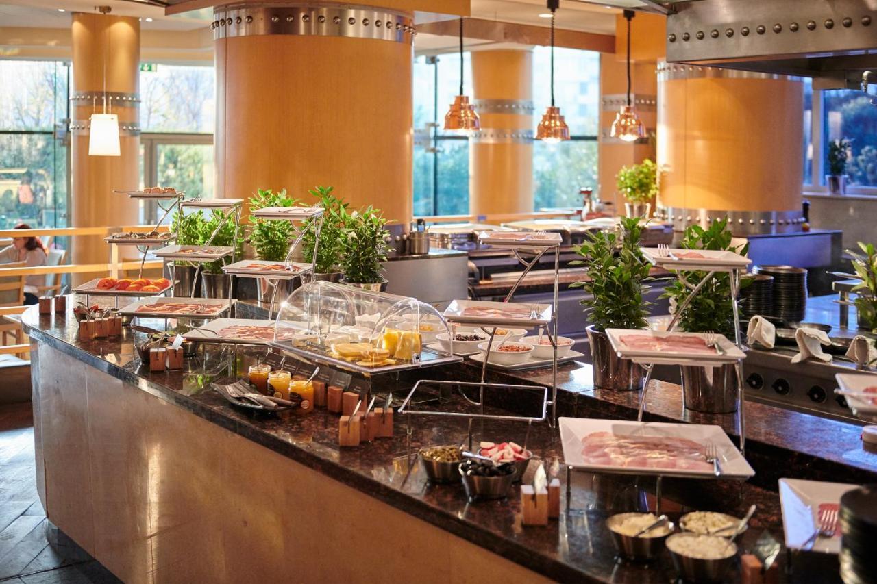 Regent Warsaw Hotel Exterior photo The photo shows a buffet setup in a restaurant or dining area. There is a long counter featuring various food items displayed in trays and covered with glass domes. The table is adorned with small potted plants, adding a touch of greenery to the spac