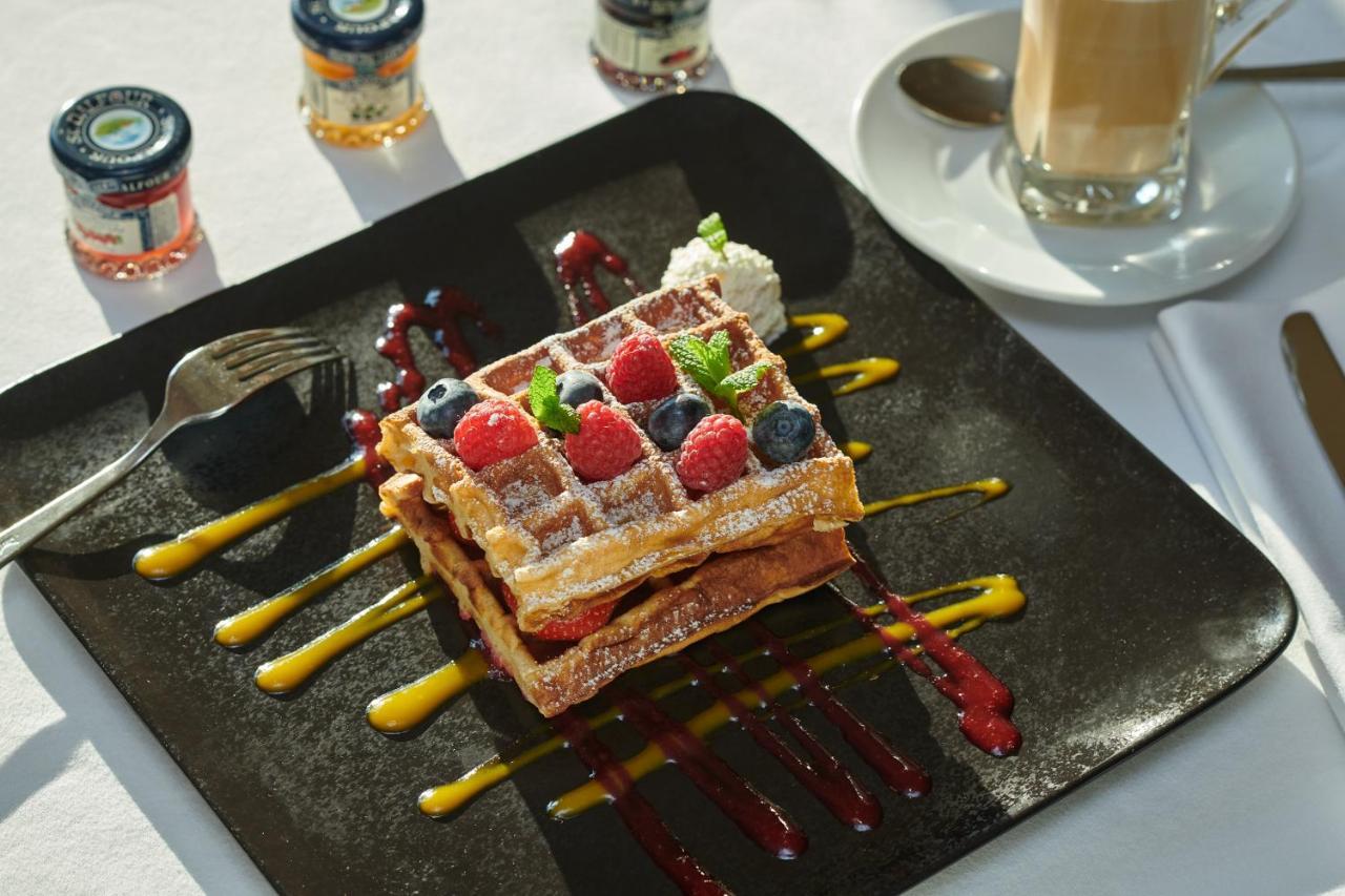 Regent Warsaw Hotel Exterior photo The photo features a delicious plate of waffles topped with a variety of fresh berries, including raspberries and blueberries. The waffles are dusted with powdered sugar and accompanied by a dollop of whipped cream. The plate is artistically arranged