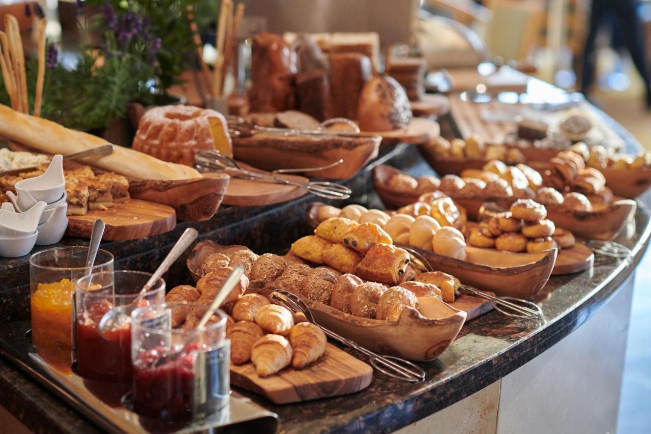 Regent Warsaw Hotel Exterior photo The photo shows a beautifully arranged spread of baked goods on a countertop. There are various types of bread, pastries, and rolls displayed on wooden boards and in bowls. Some items appear to be sweet, while others seem savory. Additionally, there 